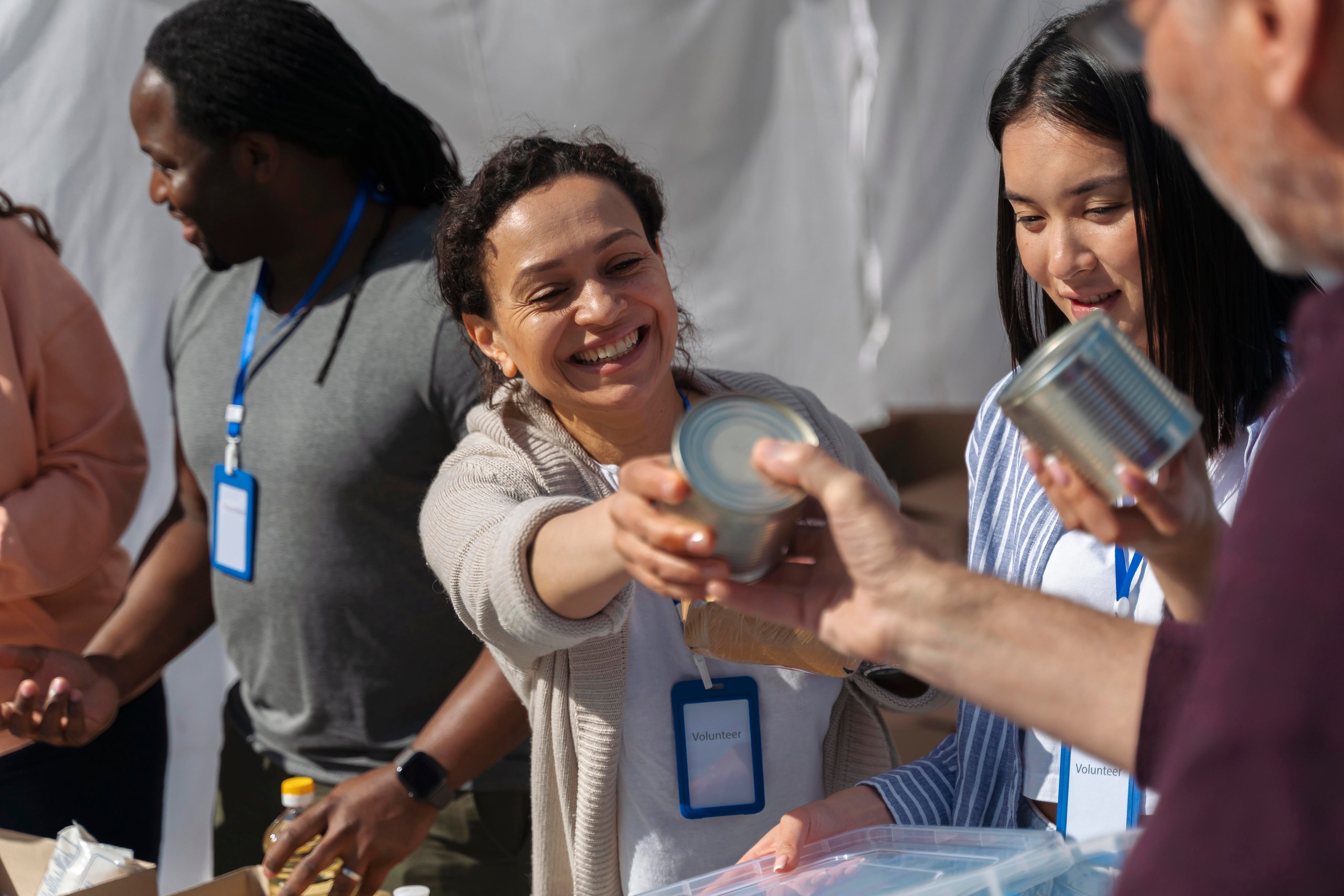 Smiling volunteers handing can food.