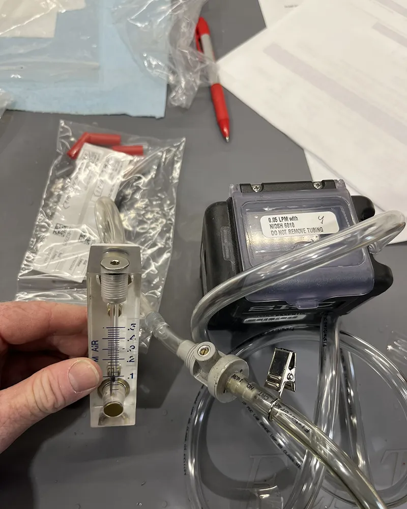 SKC AirChek Essential personal sampling pump connected to an LPM flow calibrator for industrial hygiene air monitoring