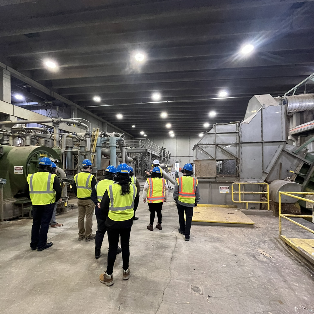 Large group of construction workers in high-visibility vests and hard hats gathering in an active jobsite warehouse for OSHA 10 and OSHA 30 safety training.