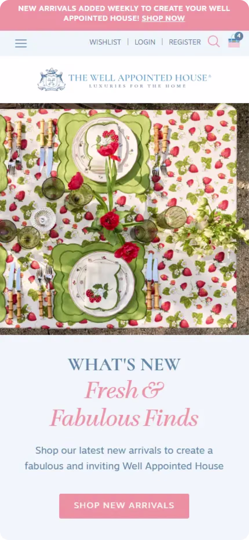 Table set with green and white plates, green glassware, floral napkins, and red flowers on a strawberry-patterned tablecloth.