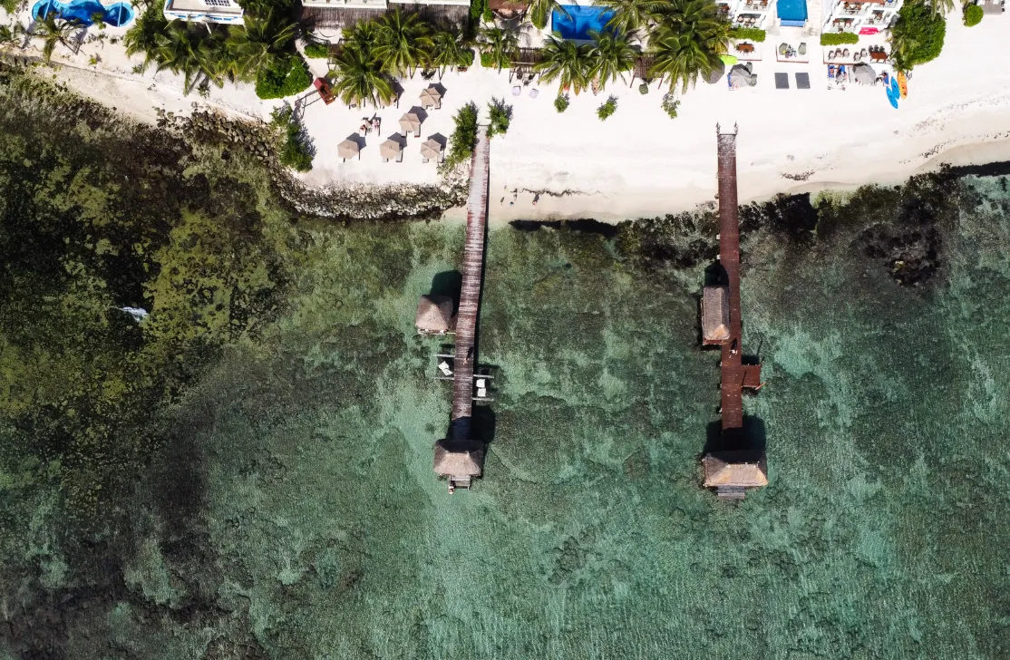Aerial view of Tulum beach piers over turquoise water from an on-location UGC shoot