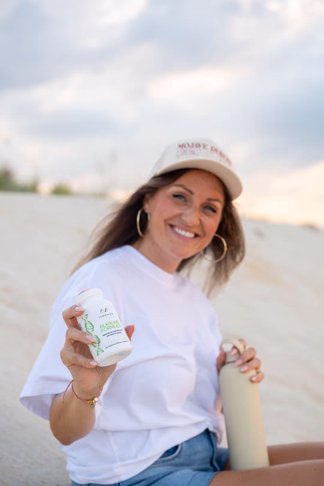 Creator in a white shirt and cap holding a client's supplement bottle while filming a UGC product video