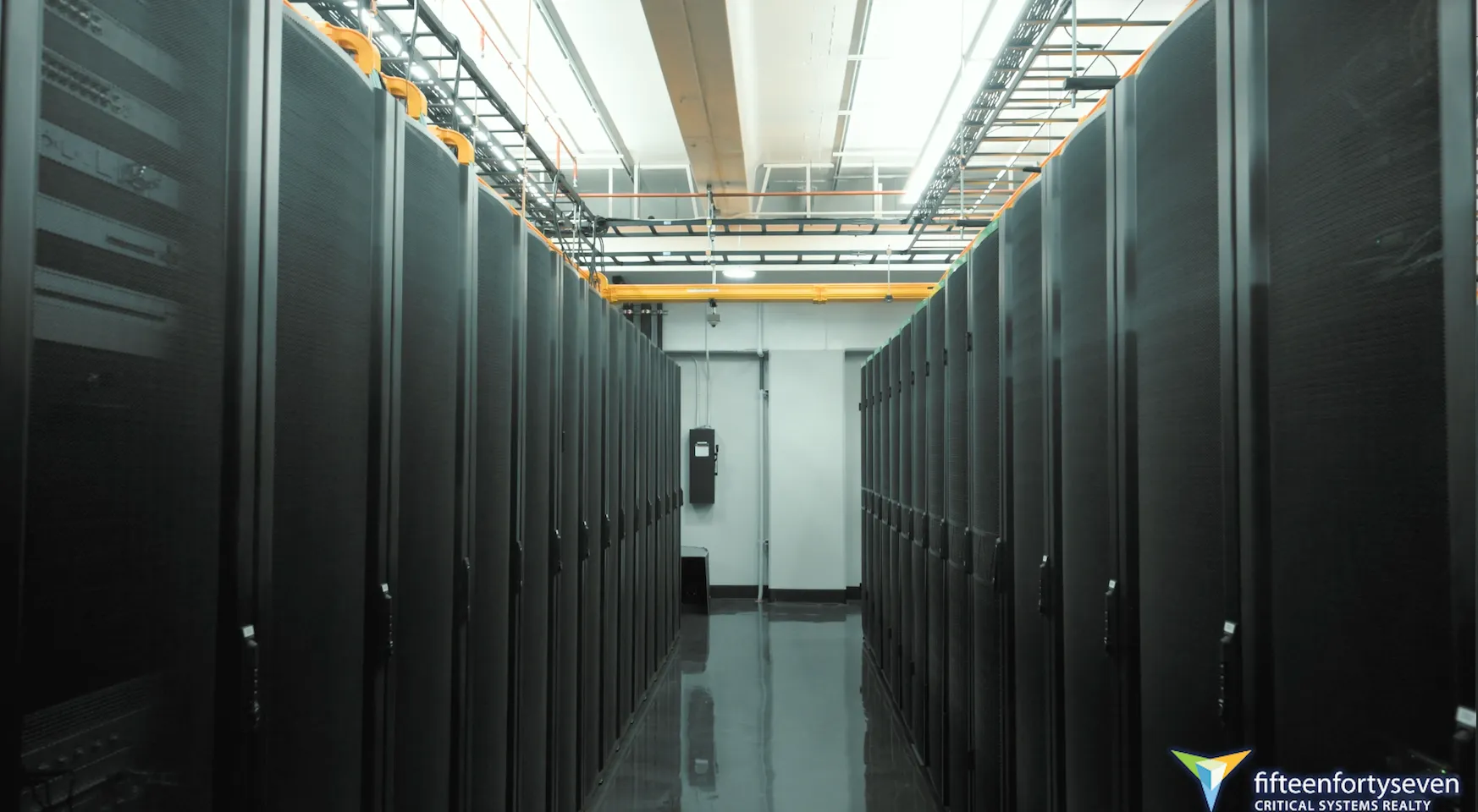 Row of black server racks inside a clean, well-lit data center hallway.