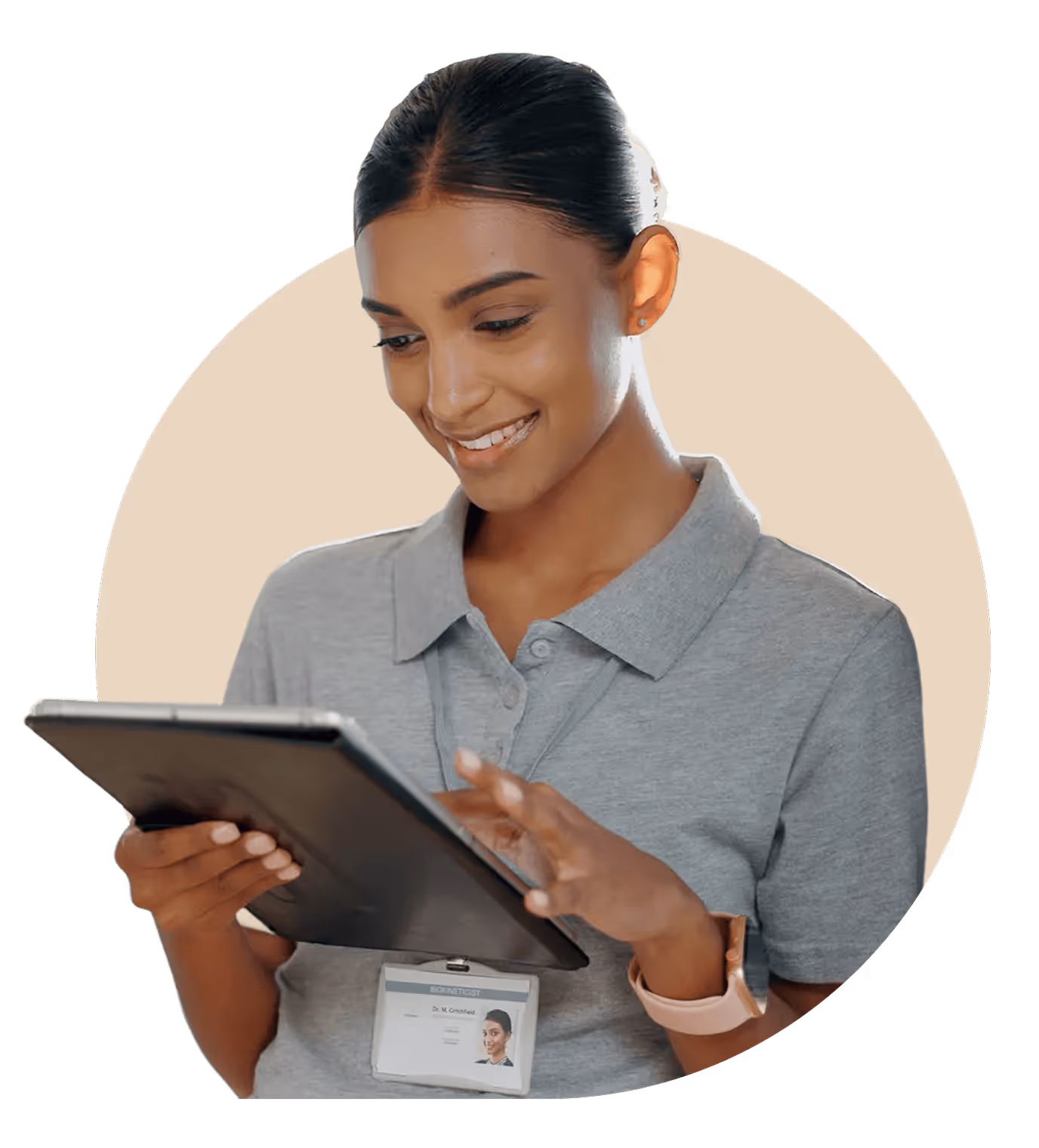 Smiling woman in gray polo shirt using a tablet with an ID badge clipped to her shirt.