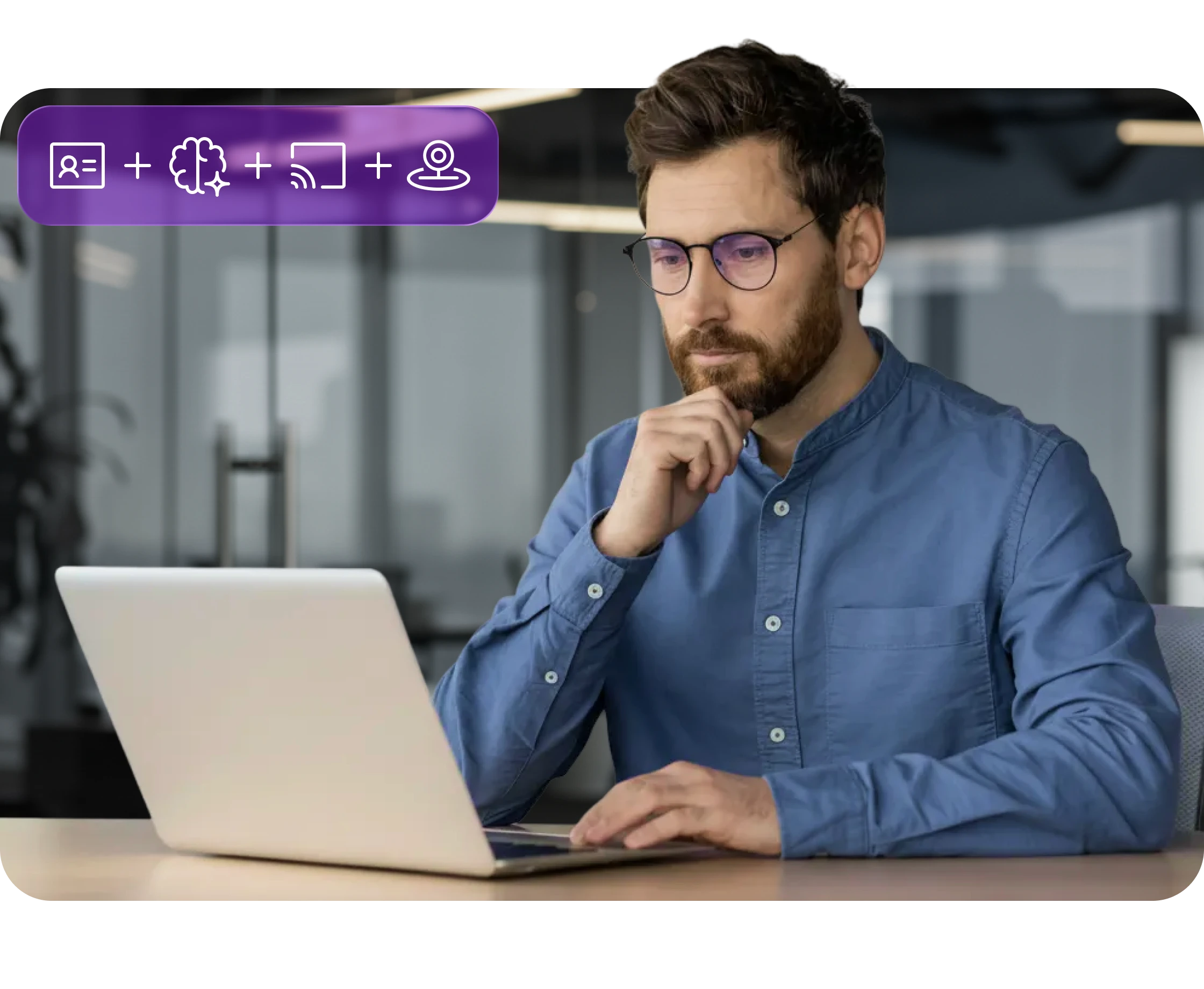 Man with glasses in blue shirt working on a laptop at office desk with icons above.