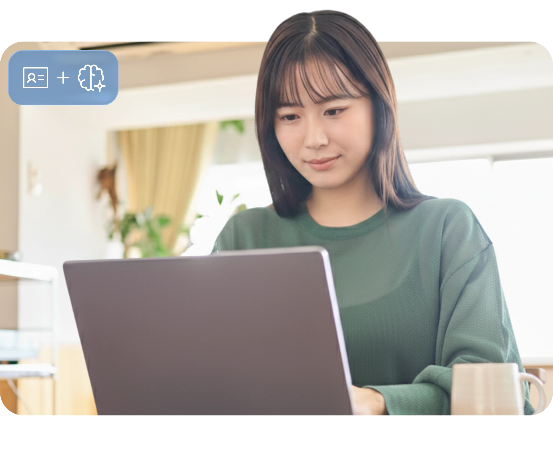 Woman in green sweater working on a laptop at a bright, cozy home setting with plants in the background.