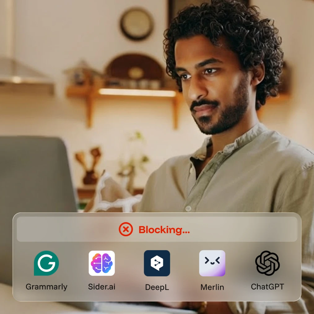 Man looking at laptop screen with a pop-up showing blocking of apps including Grammarly and ChatGPT.