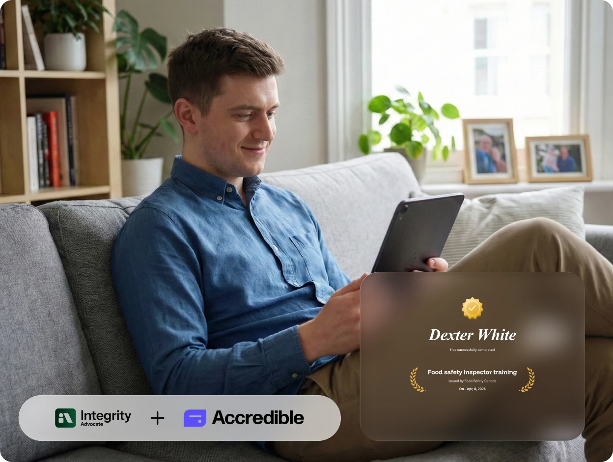 Man in blue shirt sitting on sofa, smiling while using tablet with digital food safety certificate visible.