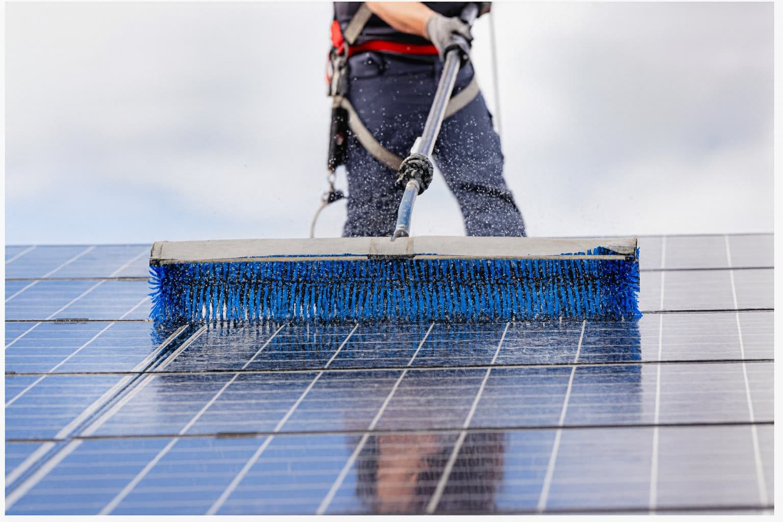 Person washing solar panel as part of a maintenance plan.