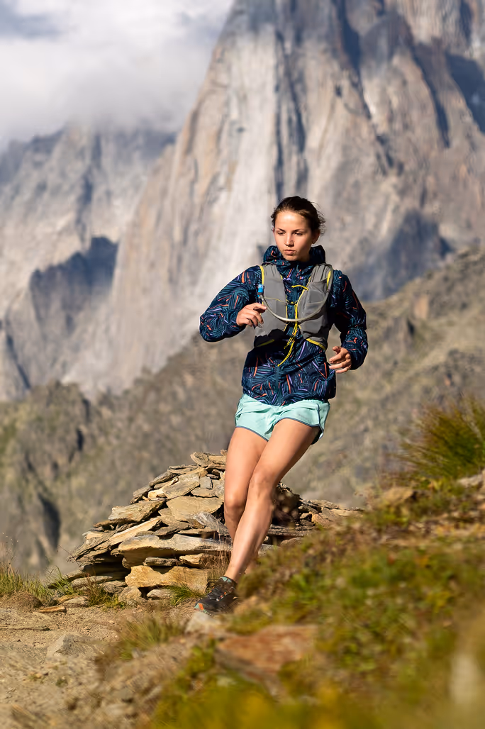 A mountain athlete performing a deep hip flexor stretch outdoors with a mountain landscape in the background