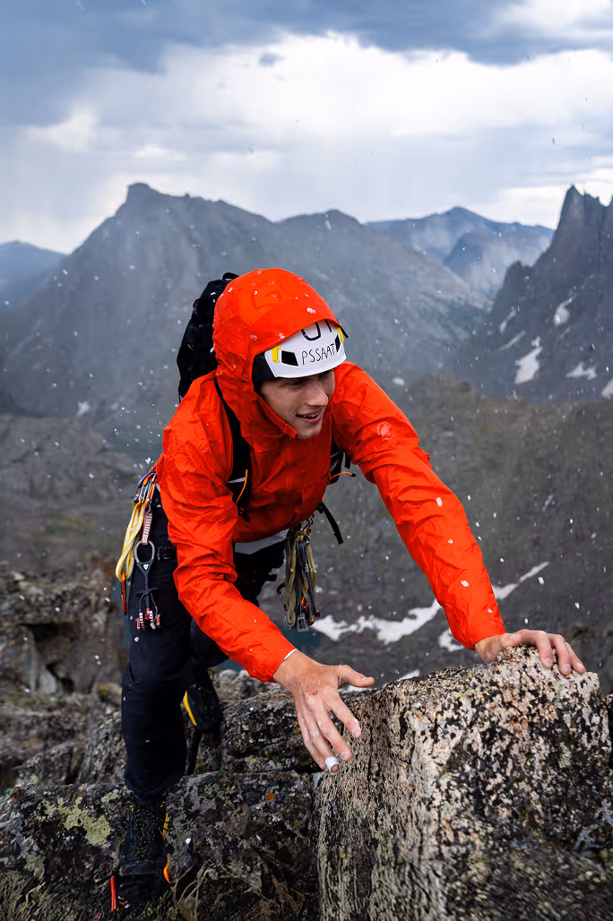 A climber navigating a steep rocky face using hands and feet on an alpine rock climbing route
