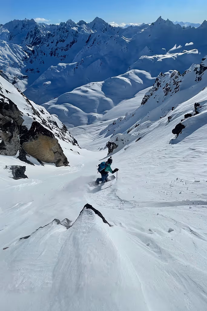 Split boarder riding down snowy mountain