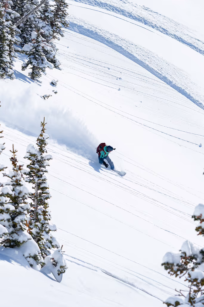 Split boarder riding down snowy mountain