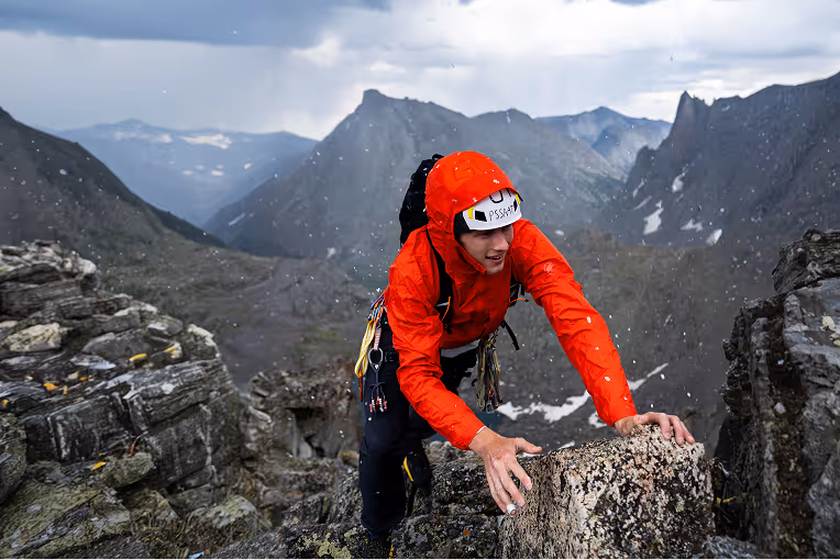 A climber navigating a steep rocky face using hands and feet on an alpine rock climbing route