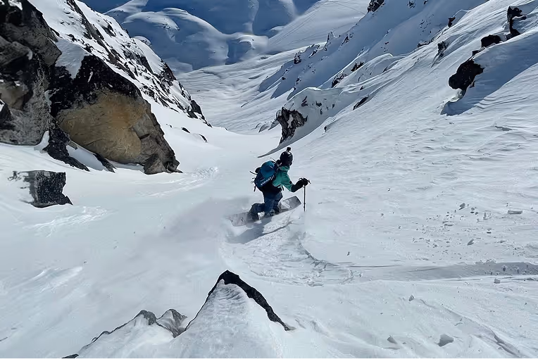 Split boarder riding down snowy mountain