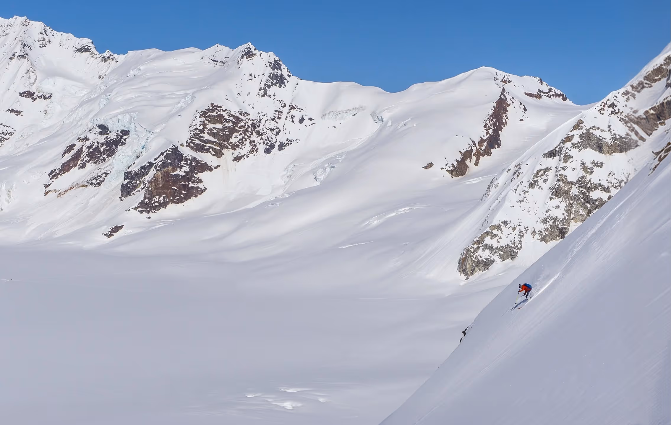 Skier riding down a snowy mountain with a scenic mountain view in the background