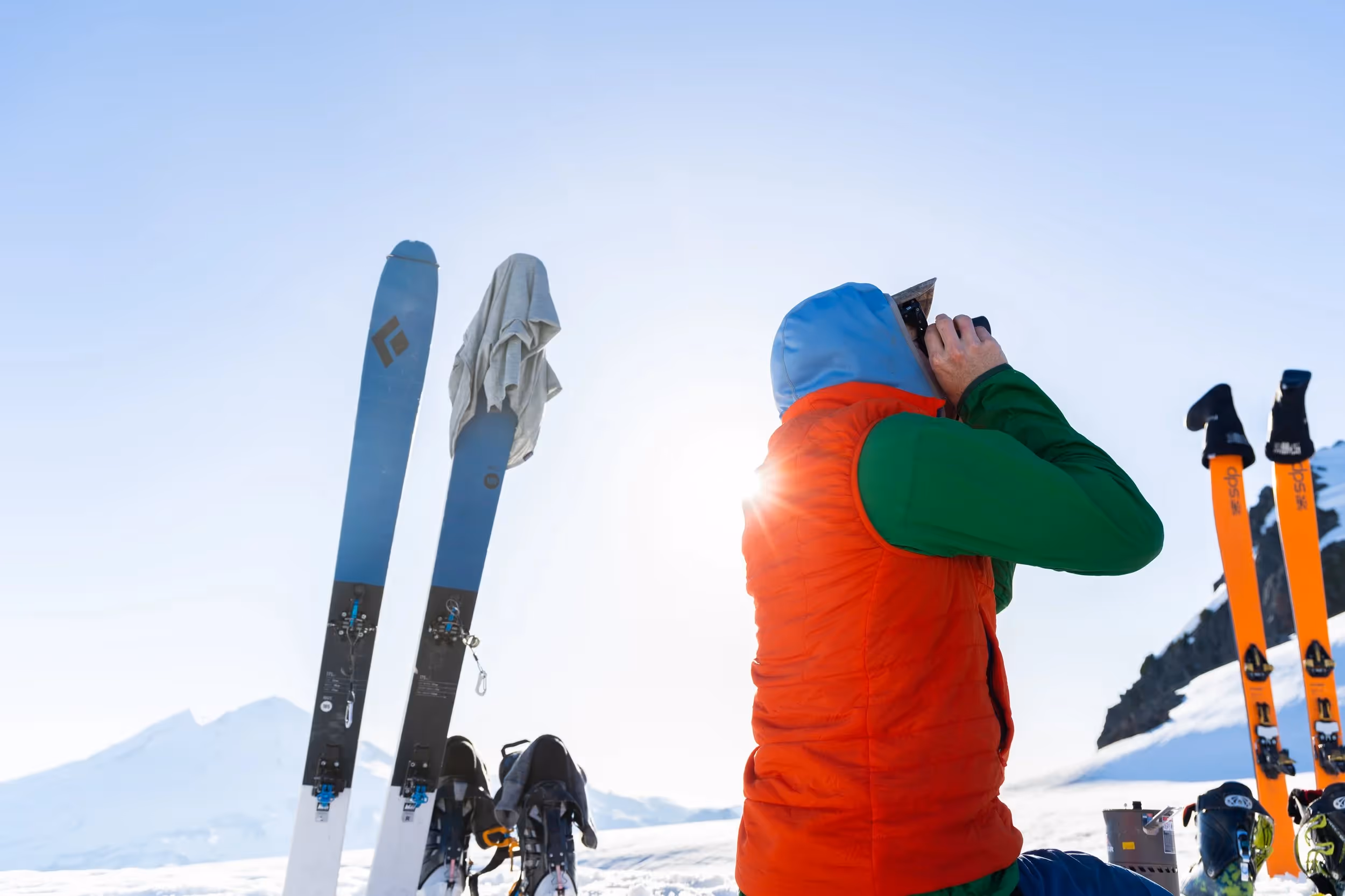 A lone climber ascending a vast, glaciated volcano in winter conditions, with a wide open sky and sweeping snowy slopes stretching into the distance