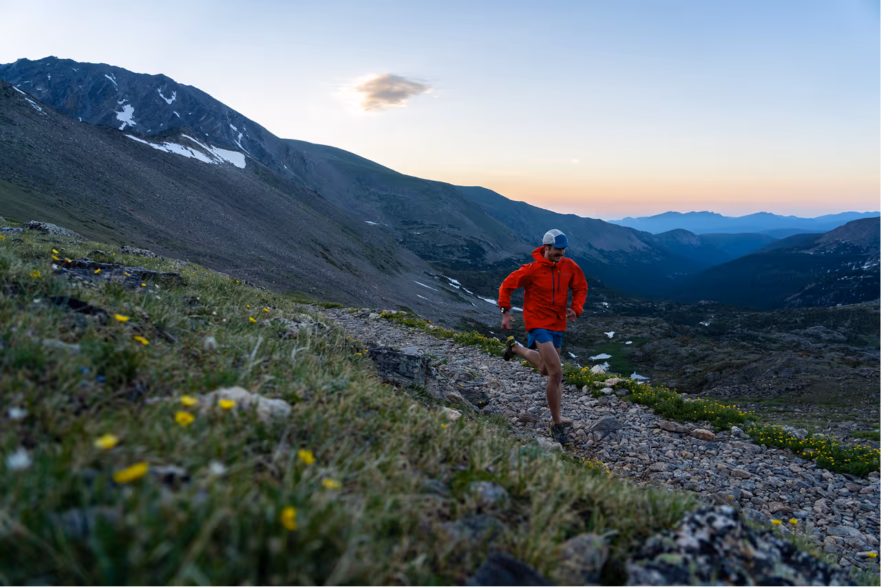 Mountain athletes running on a mountainous trail with a scenic mountain panorama behind them