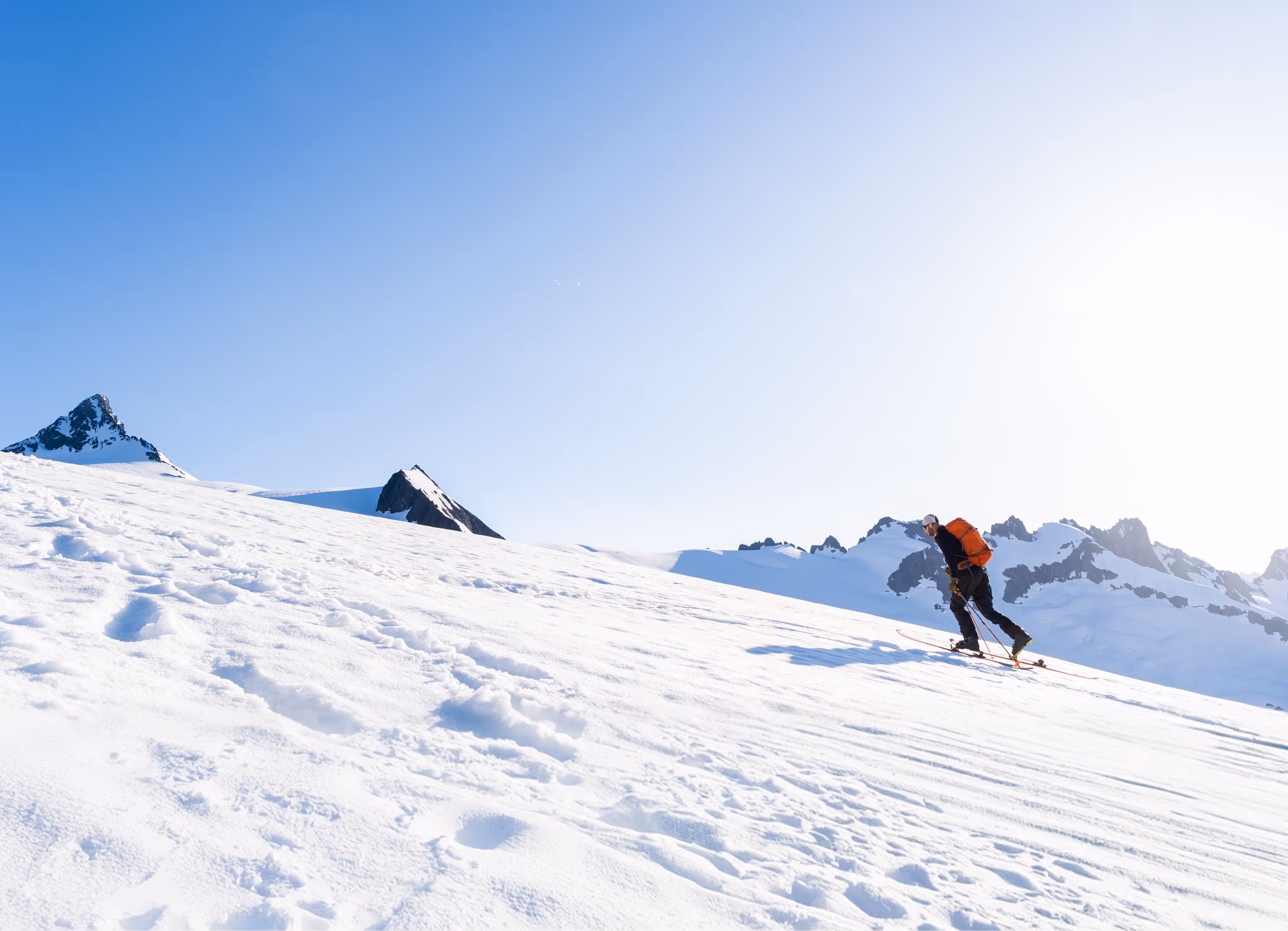 Skier hiking up a snowy mountain with a scenic mountain view in the background