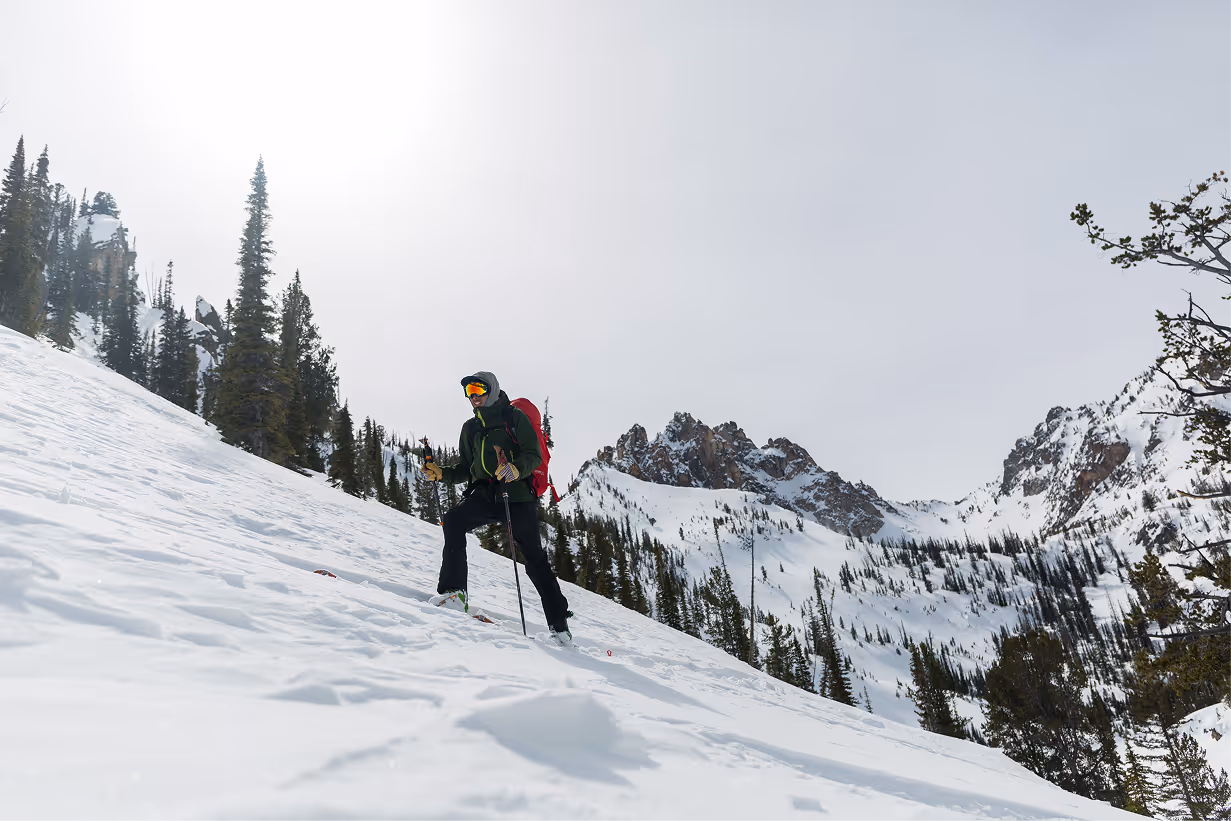 Skier hiking up a snowy mountain with a scenic mountain view in the background