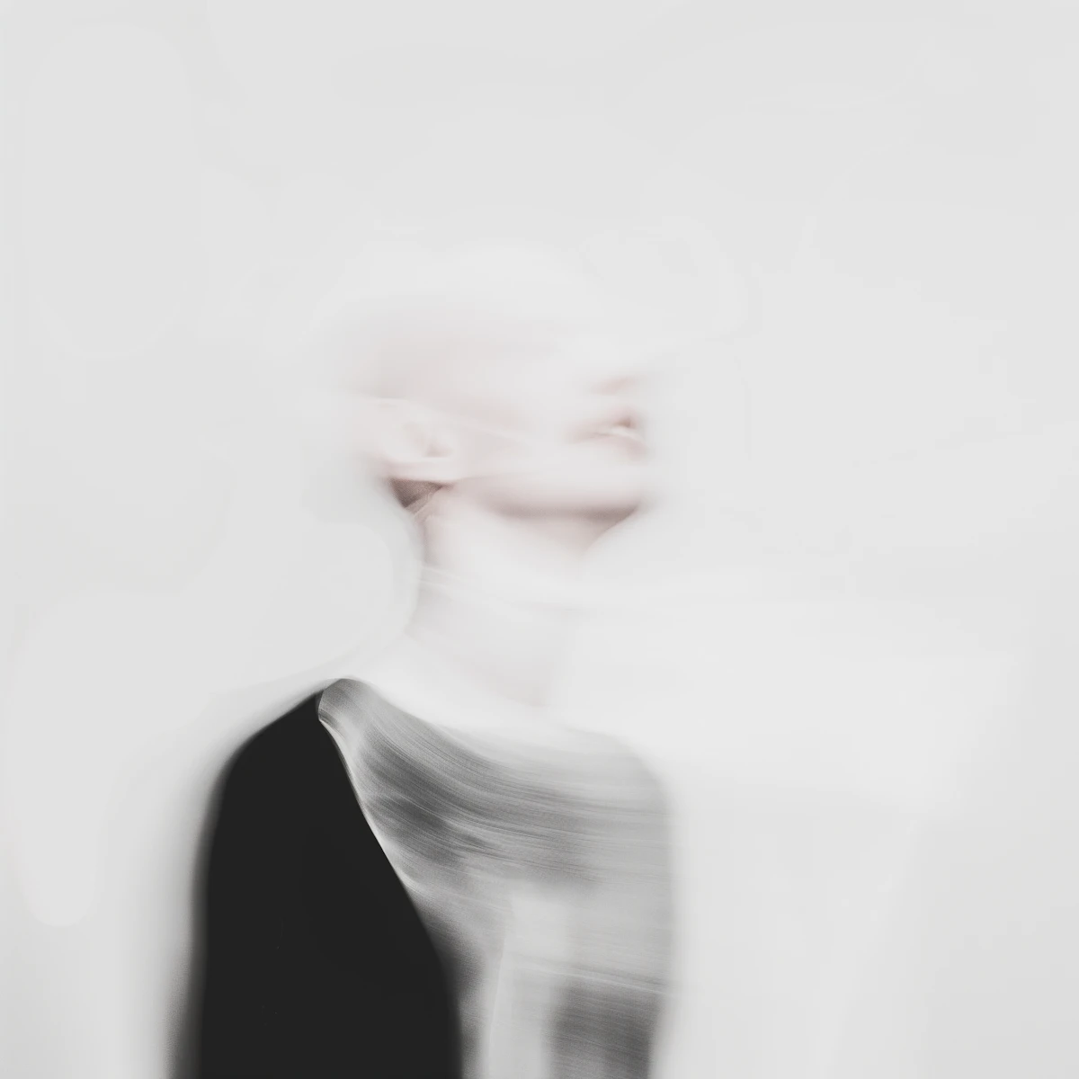 Abstract blurry portrait of a person in white tones against a bright background.