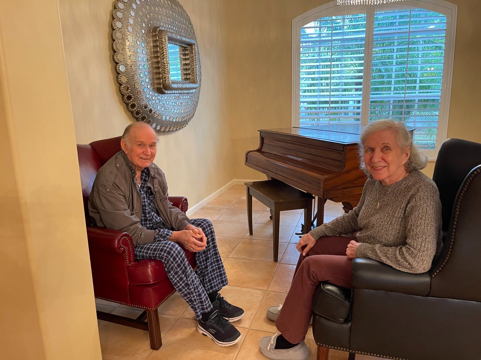 Two residents relaxing together in the living room of an Amazing Grace Assisted Living home in Palm Beach County, Florida