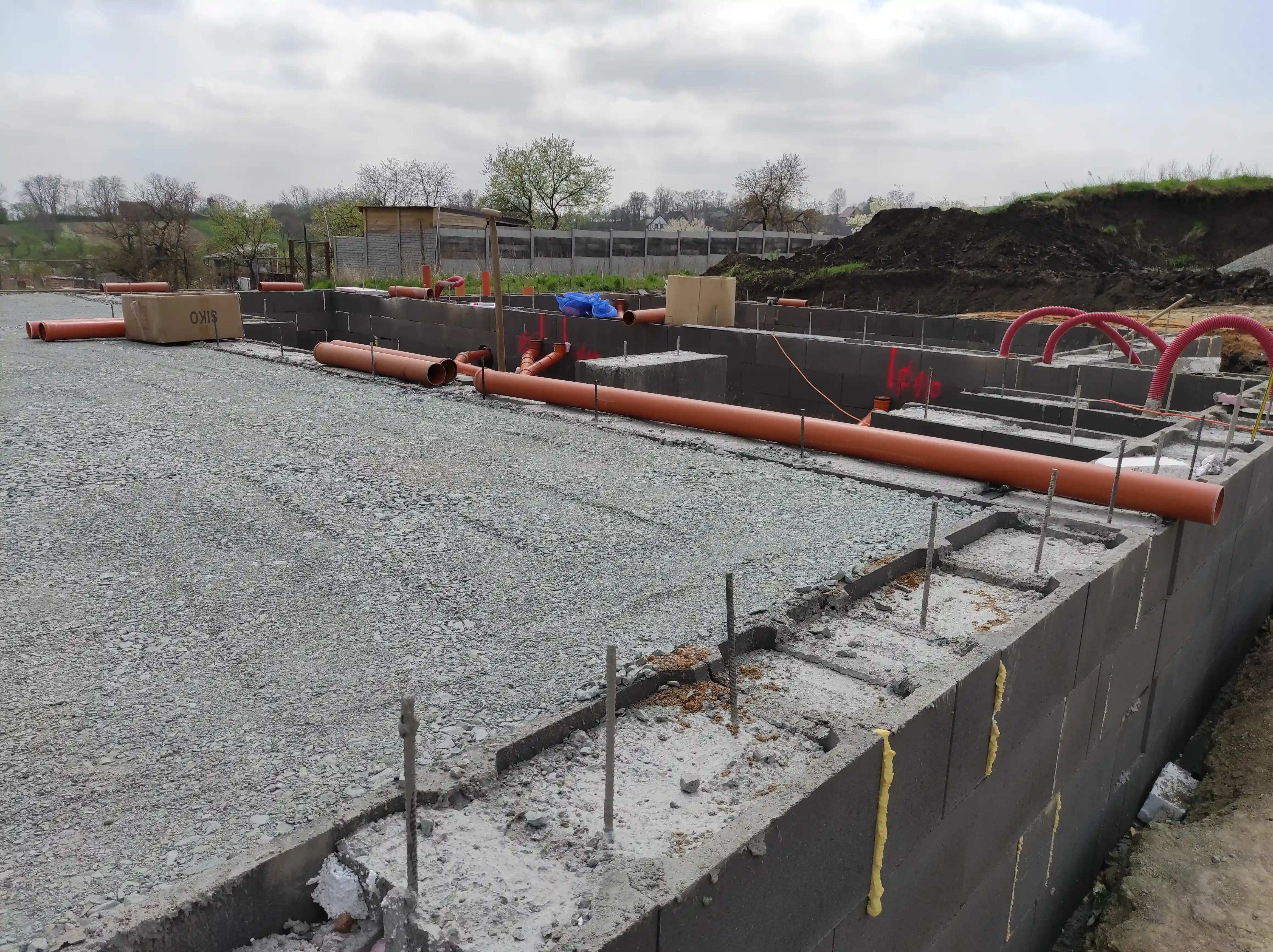 Hrubá stavba řadových domů s připravenou konstrukcí střechy a uskladněným stavebním materiálem