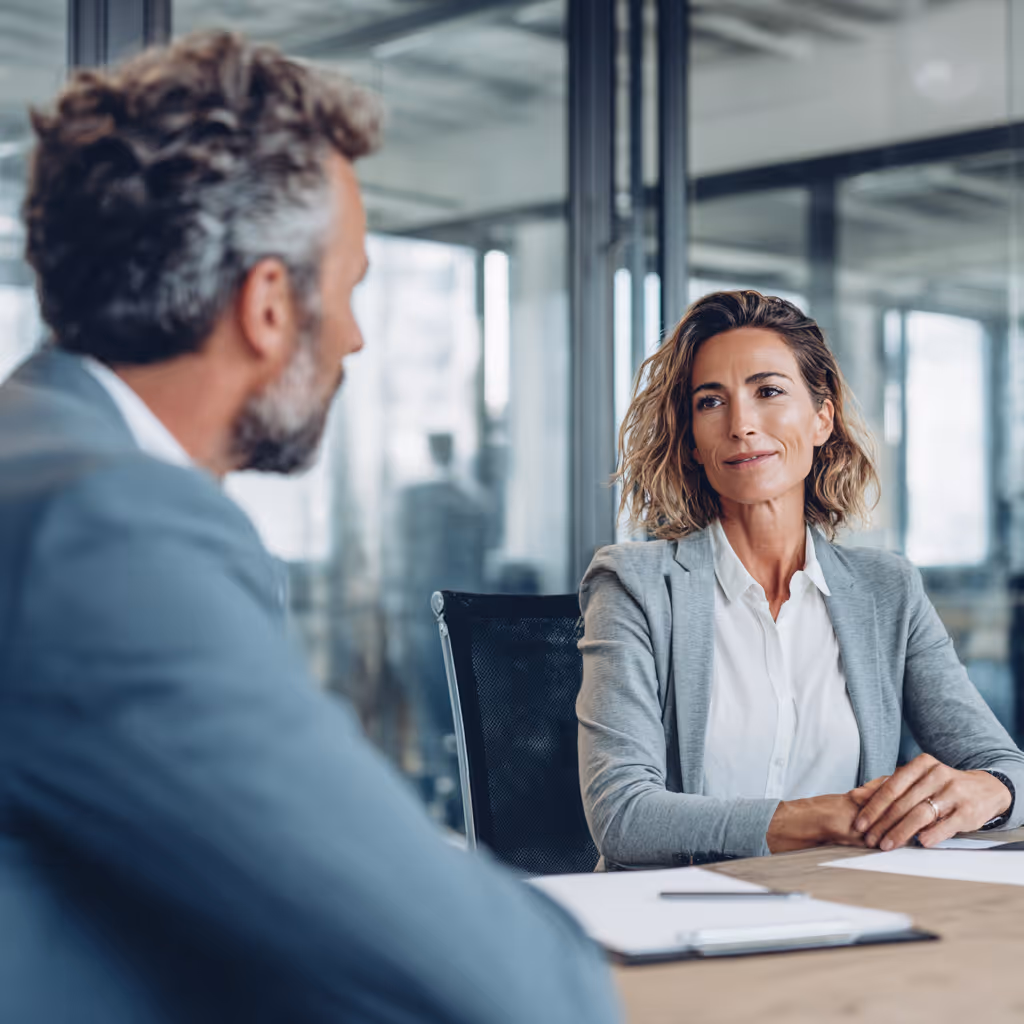 Two business professionals having a conversation in a modern office meeting room.
