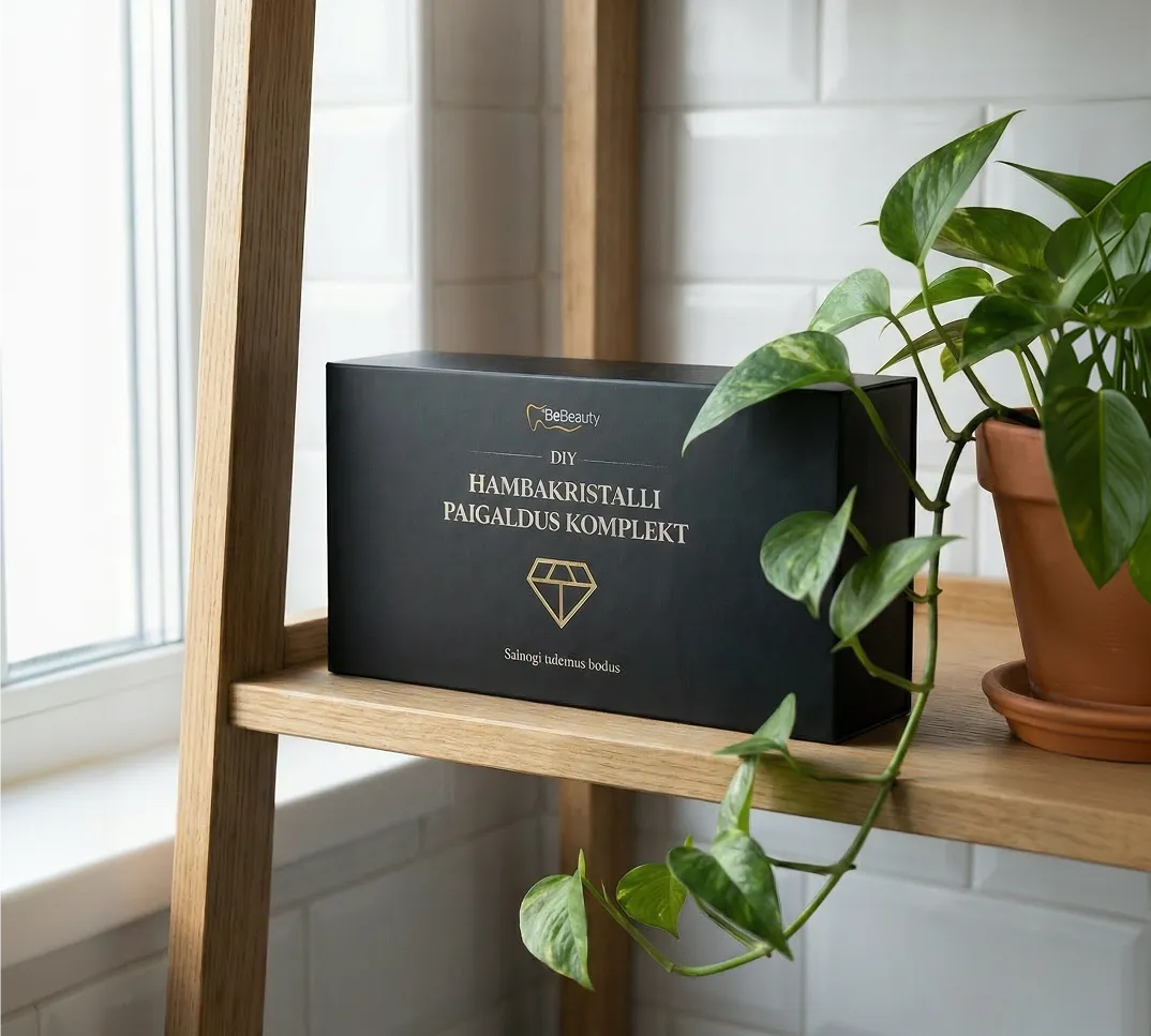 Black box labeled DIY Hambakristalli Paigaldus Komplekt with a gold diamond logo on a wooden shelf next to a potted green plant.