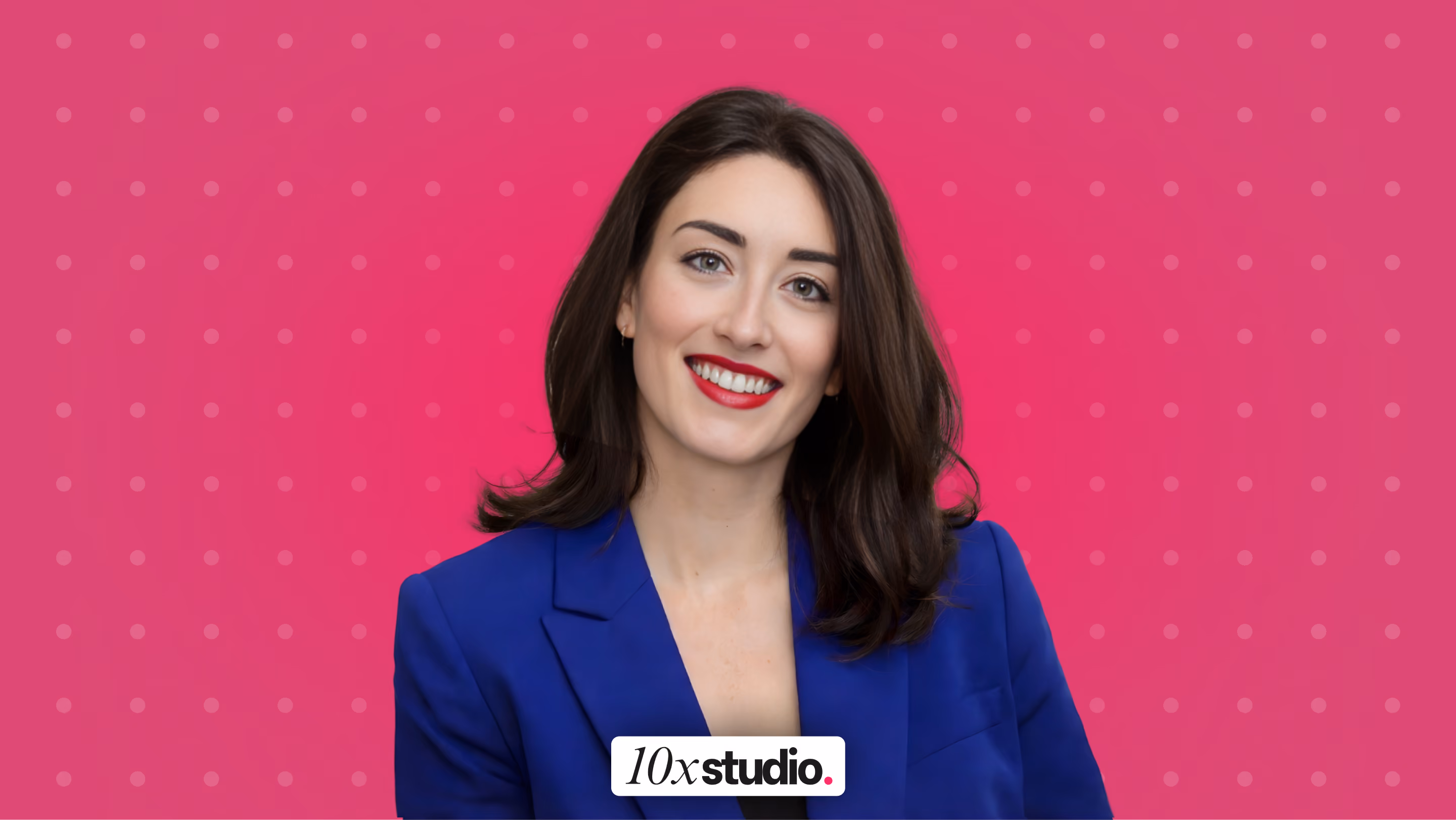 Smiling woman with dark hair wearing a blue blazer against an orange polka dot background.