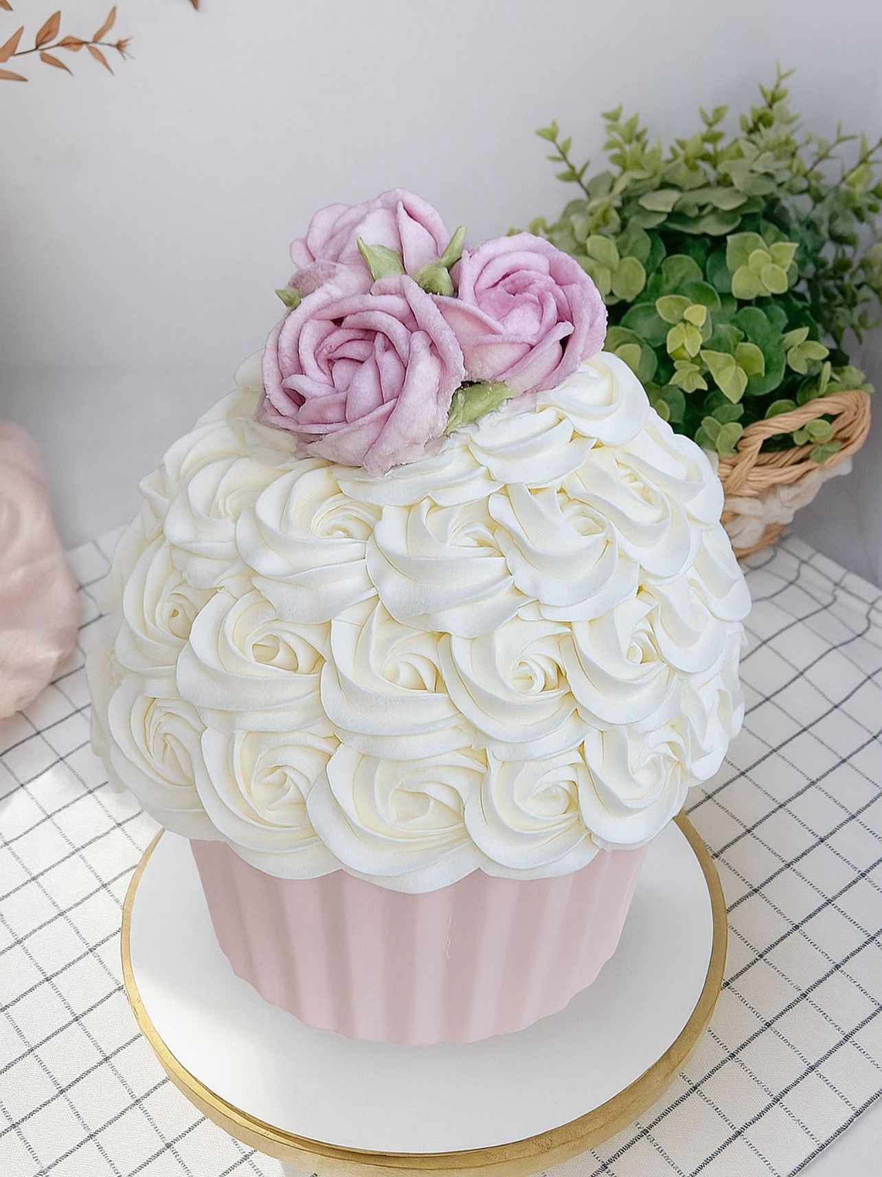 Birthday cake with pink, white, and green floral frosting and text reading 'Happy Birthday Anais 20', accompanied by two matching cupcakes with pink flower frosting in a white box.