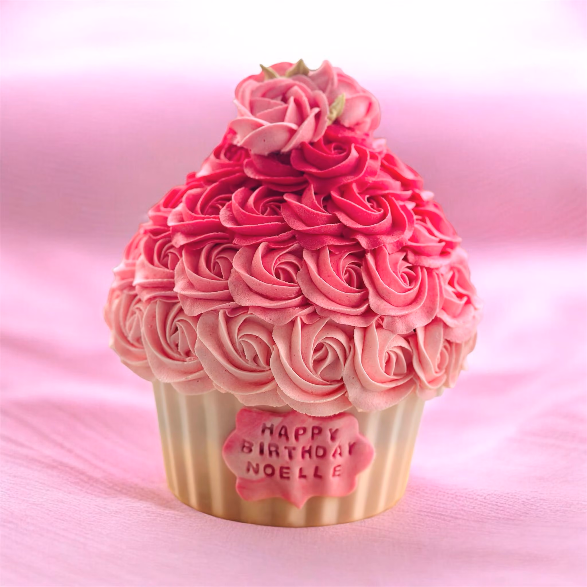 Birthday cake with pink, white, and green floral frosting and text reading 'Happy Birthday Anais 20', accompanied by two matching cupcakes with pink flower frosting in a white box.