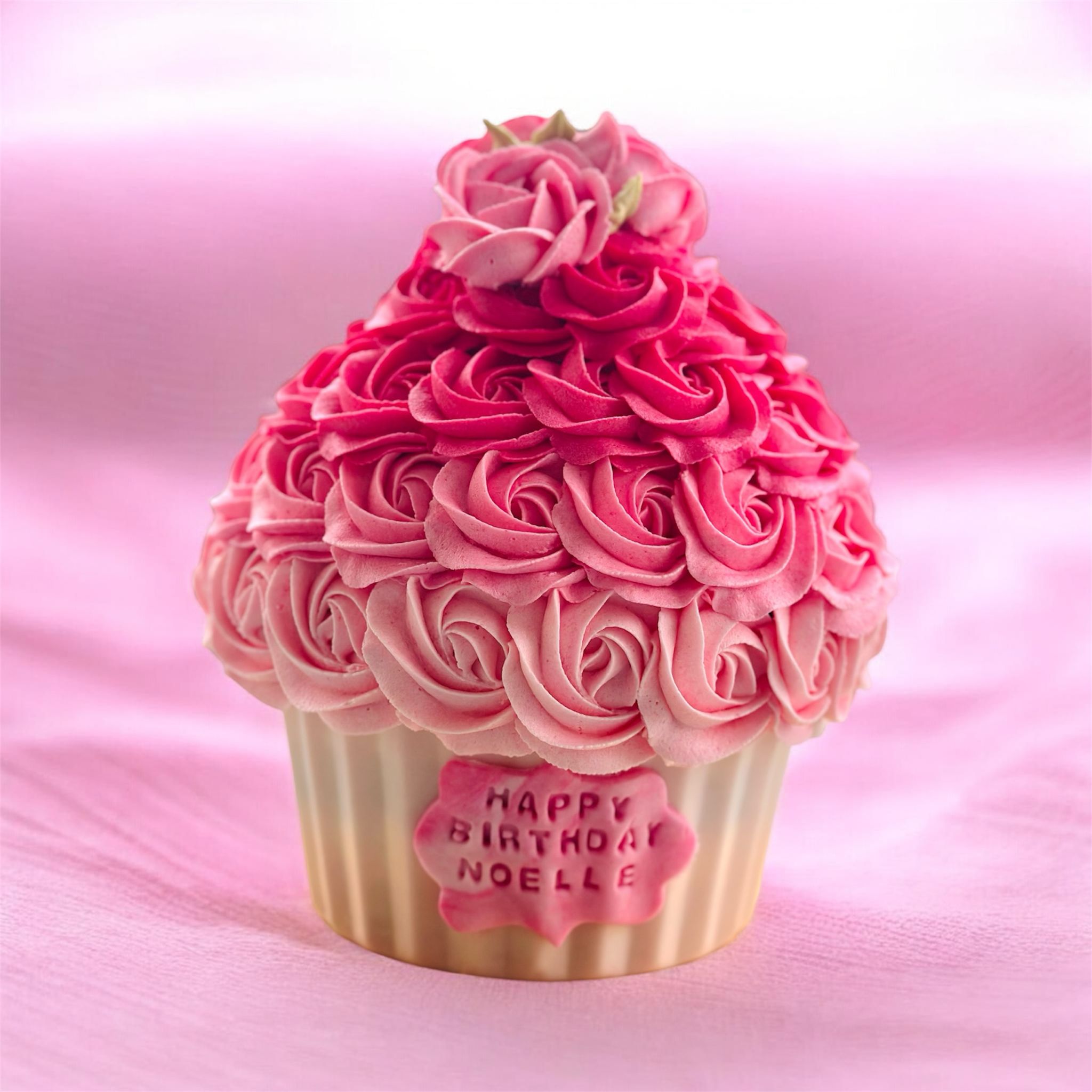 Birthday cake with pink, white, and green floral frosting and text reading 'Happy Birthday Anais 20', accompanied by two matching cupcakes with pink flower frosting in a white box.