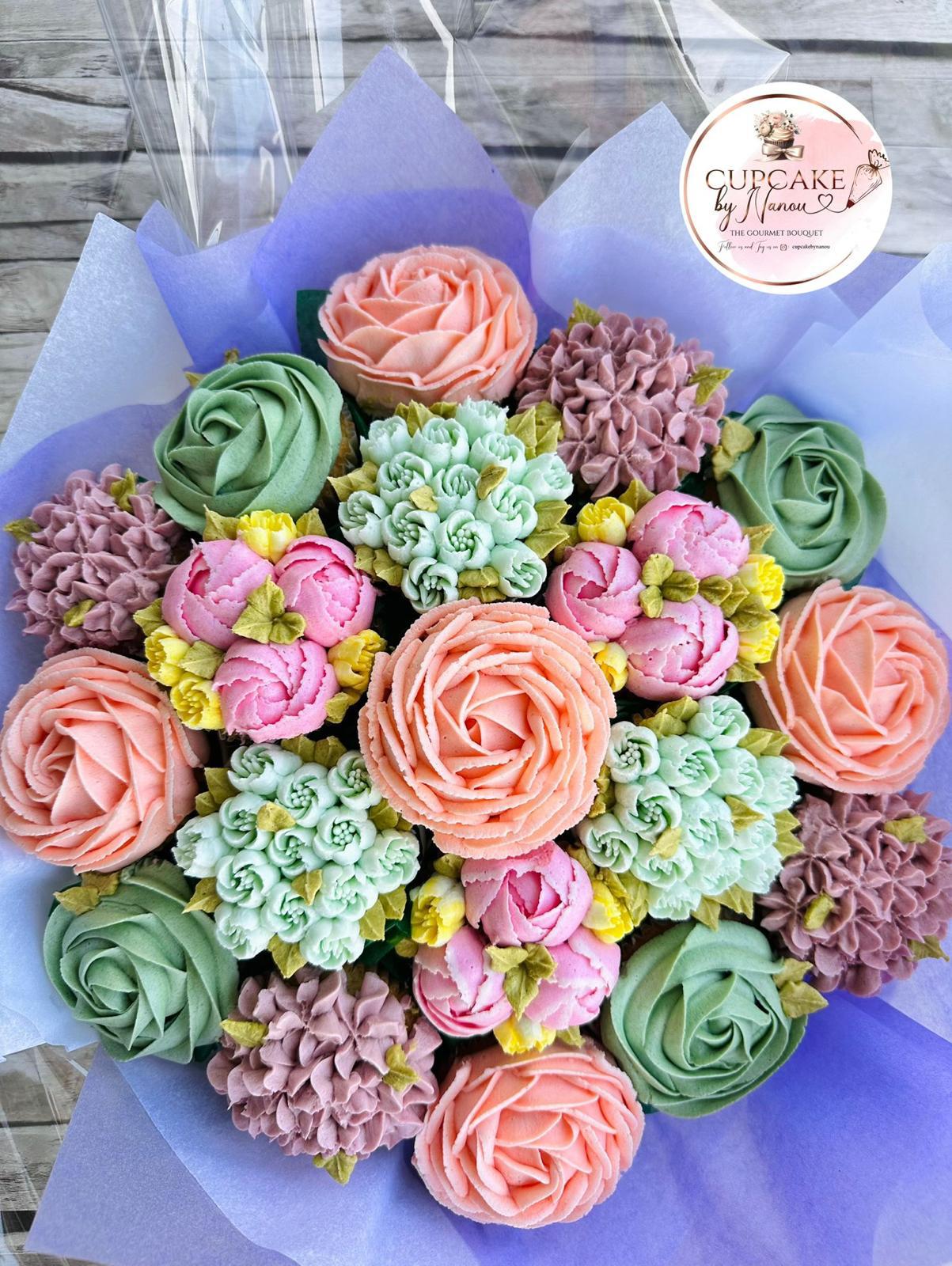 Bouquet of intricately decorated cupcakes with orange and pink floral frosting and green leaves.