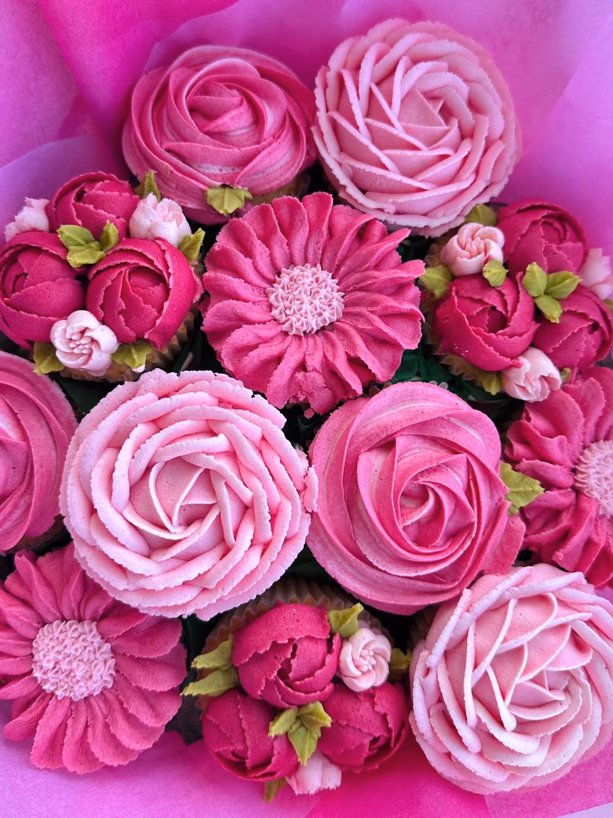 Box of assorted cupcakes and a small round cake with purple, pink, gray, and white floral frosting, with the cake inscribed 'Happy birthday CHITTI'.