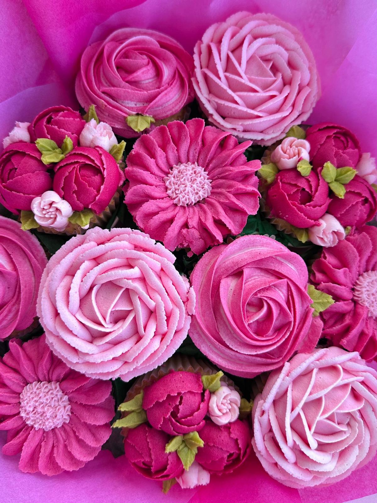 Box of assorted cupcakes and a small round cake with purple, pink, gray, and white floral frosting, with the cake inscribed 'Happy birthday CHITTI'.