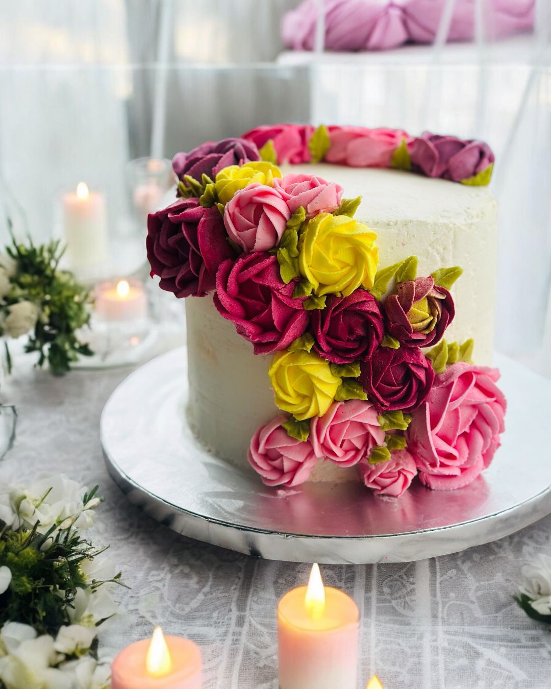 Cut pink and blue gender reveal cake with rosette frosting on a glass cake stand, displaying layered pink and purple interior.
