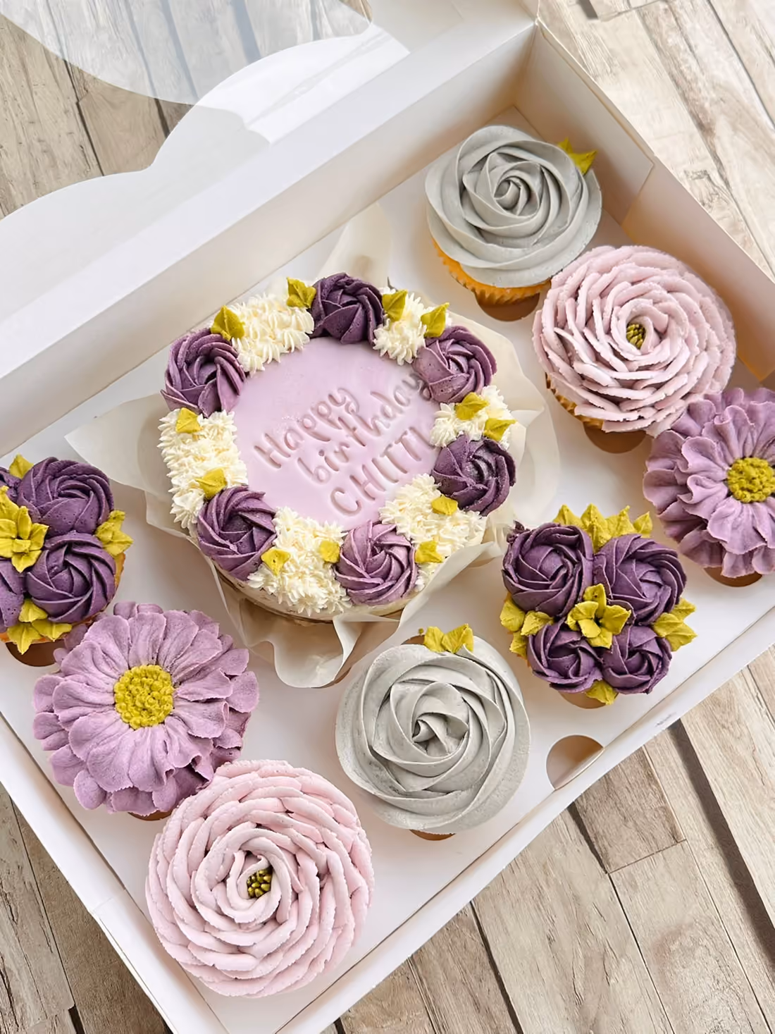 Bento cake d'anniversaire aux fleurs violettes, grises et blanches, avec ses cupcakes