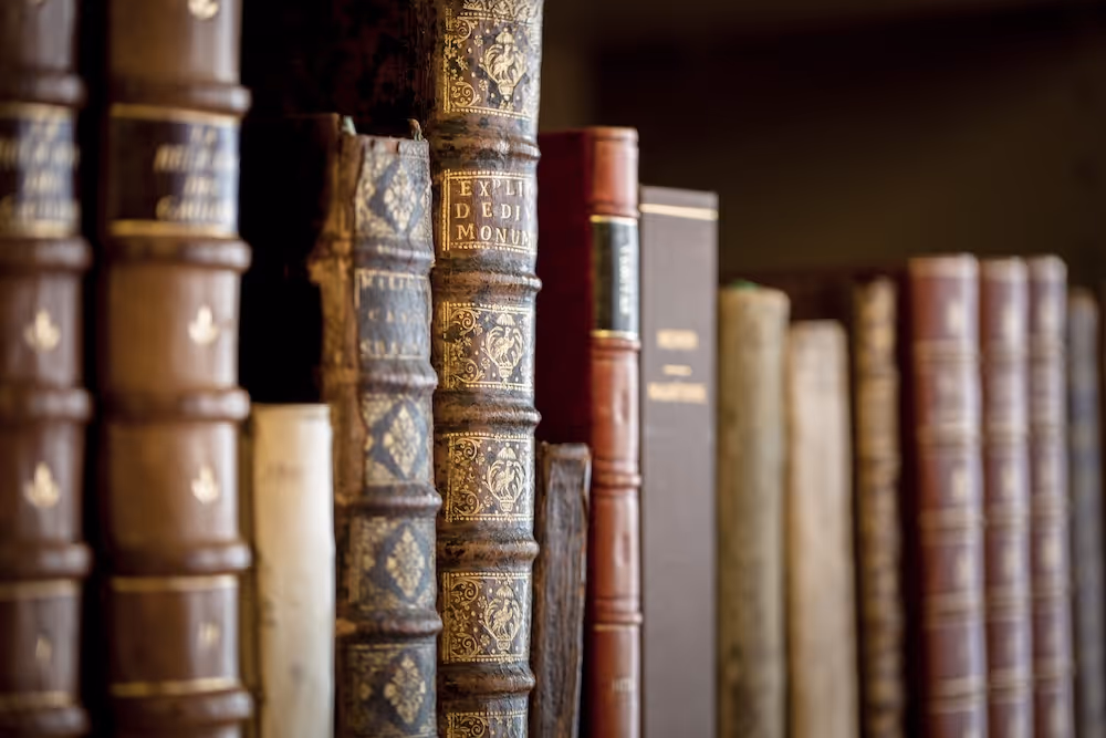 Een close-up met een kleine scherptediepte van vintage, in leer gebonden boeken die dicht op elkaar op een plank staan.