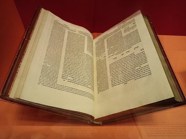 An open 1520s Bomberg Talmud book displaying columns of printed Hebrew text under soft lighting on a warm wooden table.