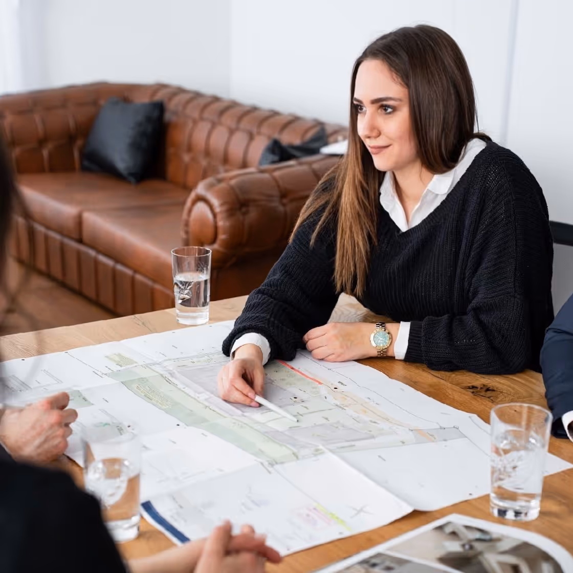 Smiling man in white shirt examines wooden flooring samples at a table in a bright room.