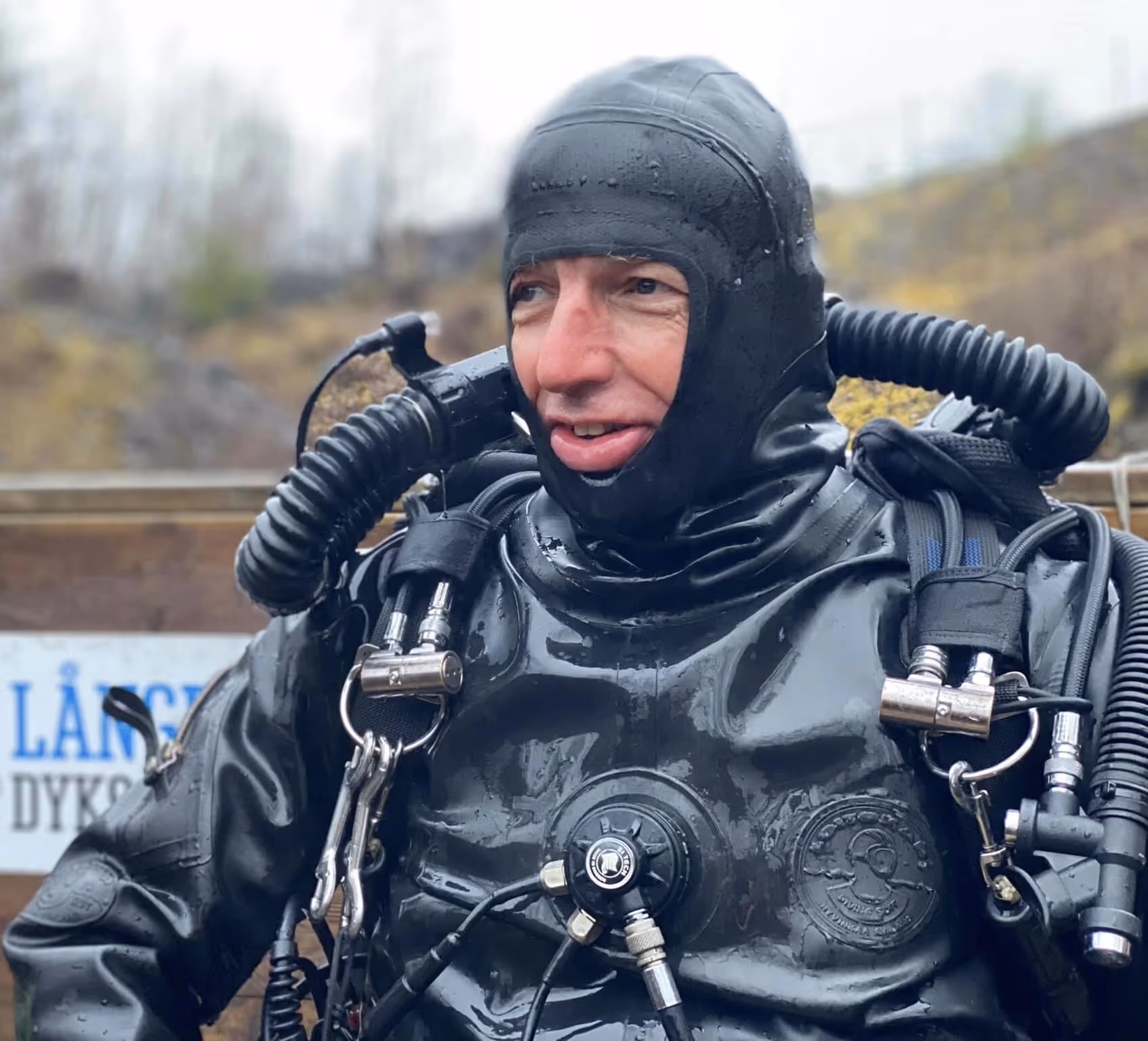 Phil Short - Close-up of a diver wearing a black drysuit with a full hood and breathing apparatus