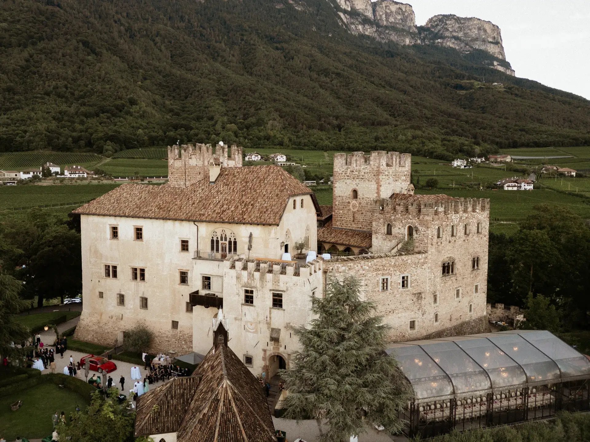 Ein altes Schloss mit mittelalterlicher Architektur umgeben von grüner Landschaft und einer Hochzeit im Freien.