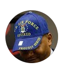 Man wearing a blue cap that says 'AIR FORCE RETIRED' and 'PROUDLY SERVED'.