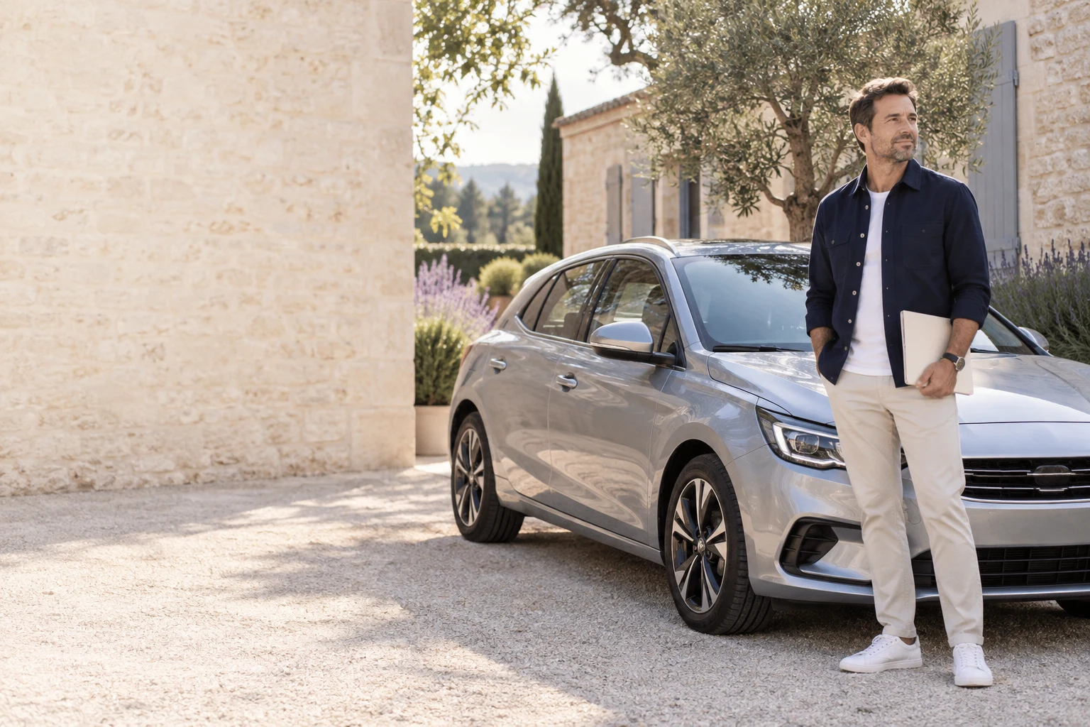 Un automobiliste prépare son dossier près de sa voiture stationnée dans une cour