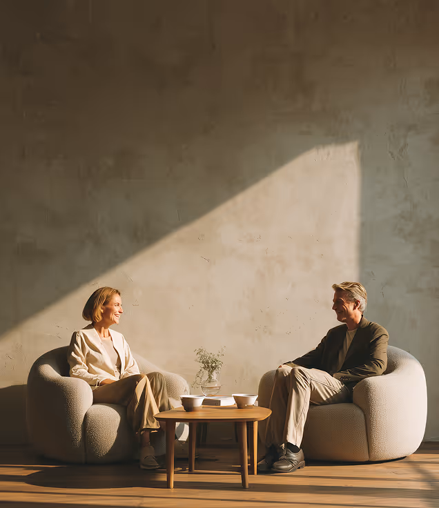 Two people seated in a bright, minimalist room with abundant natural light, showcasing refined spatial design and modern architectural aesthetics.
