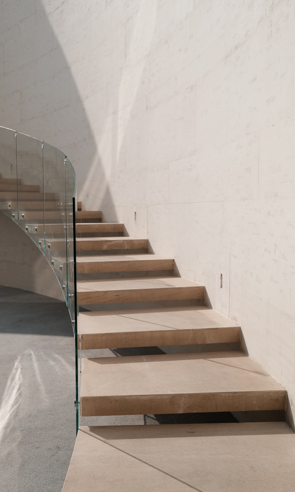 Modern staircase with glass railing and marble wall