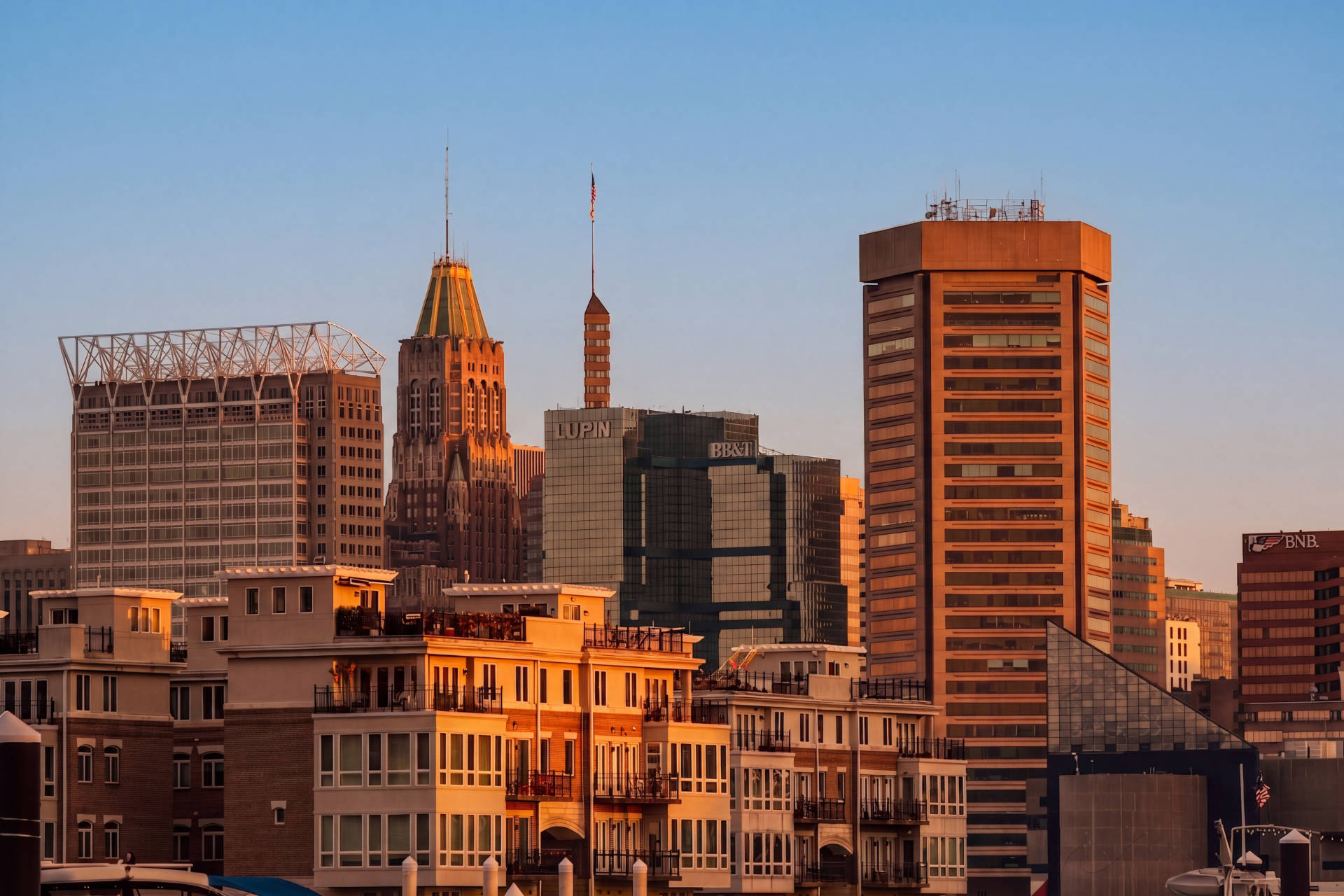 Baltimore city skyline at sunset with high-rise buildings and residential waterfront homes.