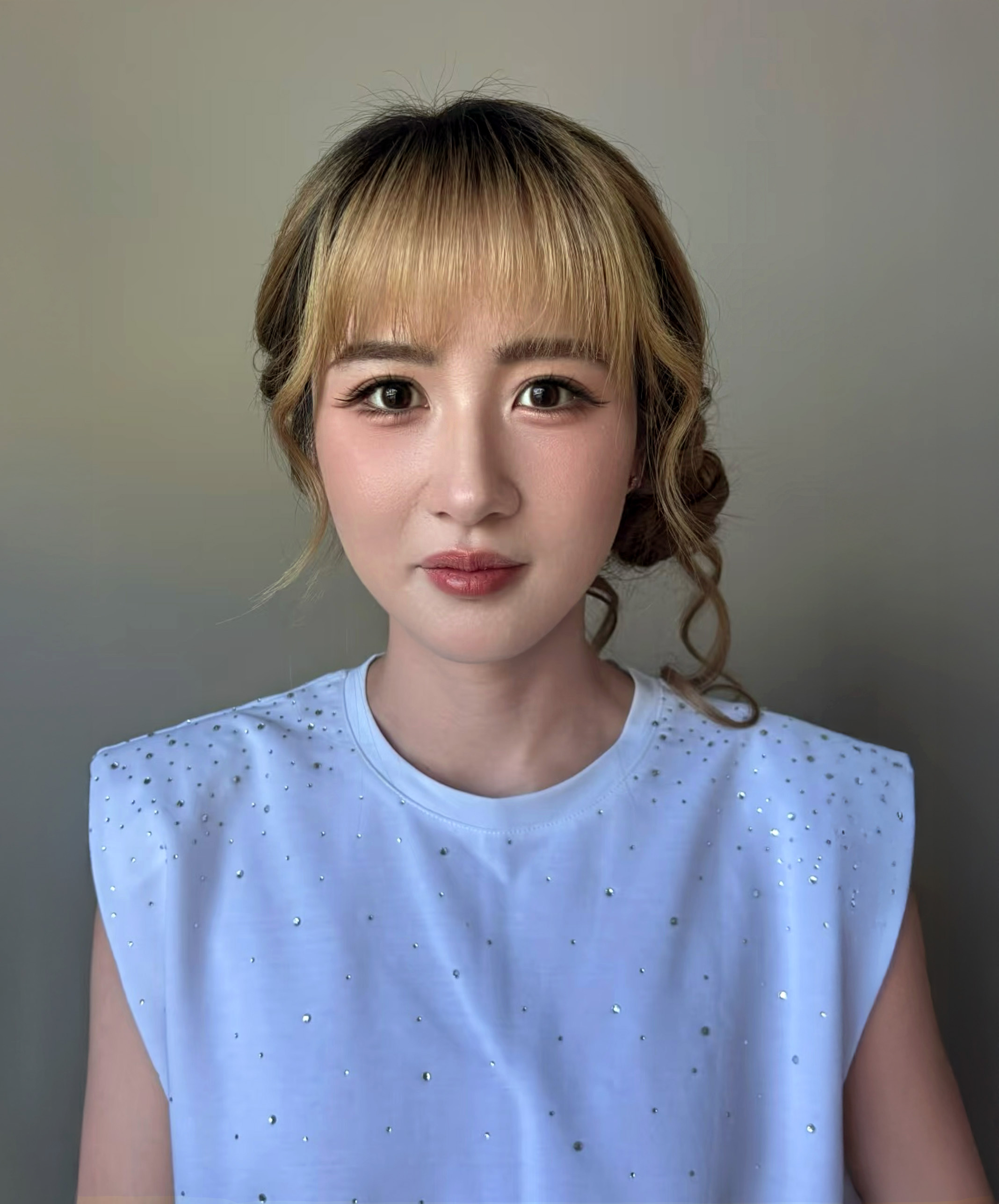 Young woman with elegant makeup and red lipstick wearing a white lace strap dress and hair accessory.