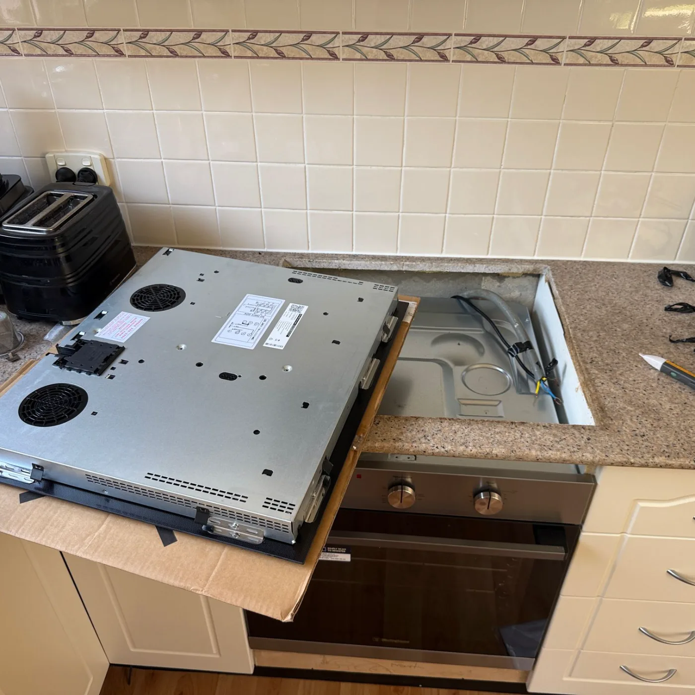 Induction cooktop being fitted into the modified benchtop